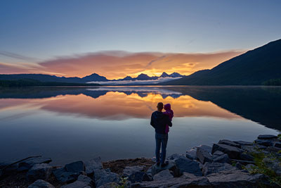 person with child overlooking majectic lake