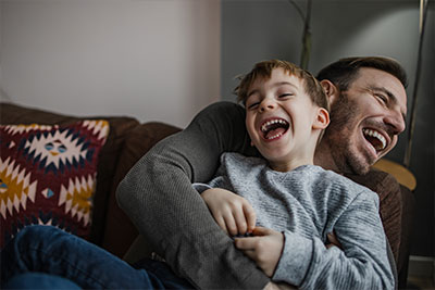 a father and son laughing on a couch