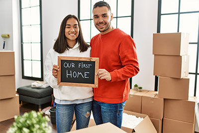 A young couple holding a first time home buying and insurance sign