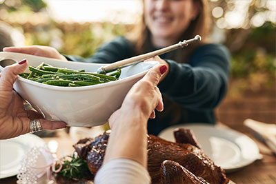 two people passing food at a holiday dinner