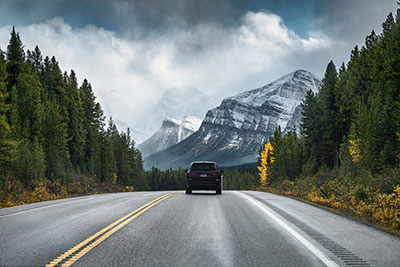 A car driving down the highway with a mountain in the background